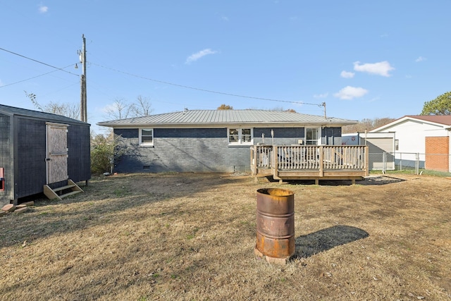 rear view of property featuring a yard, a storage shed, and a wooden deck