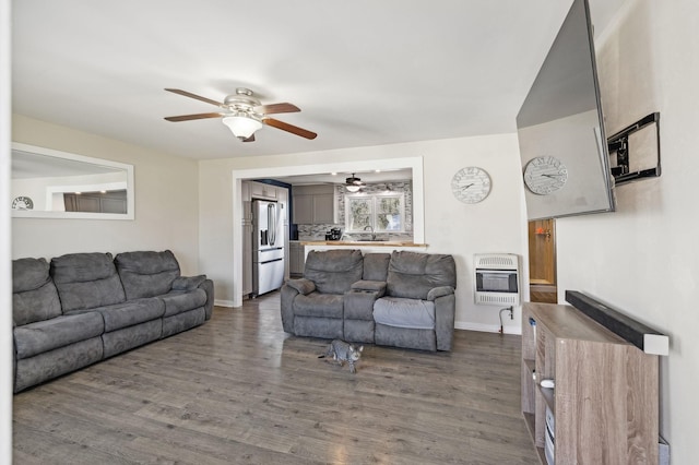 living room featuring heating unit, ceiling fan, and dark wood-type flooring