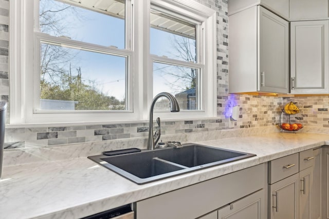 kitchen featuring gray cabinetry, decorative backsplash, sink, and light stone counters