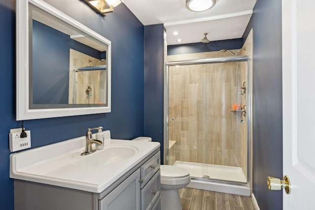 bathroom featuring vanity, wood-type flooring, an enclosed shower, and toilet