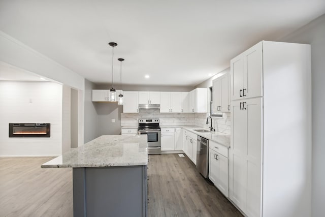 kitchen featuring a center island, dark hardwood / wood-style floors, a fireplace, white cabinets, and appliances with stainless steel finishes