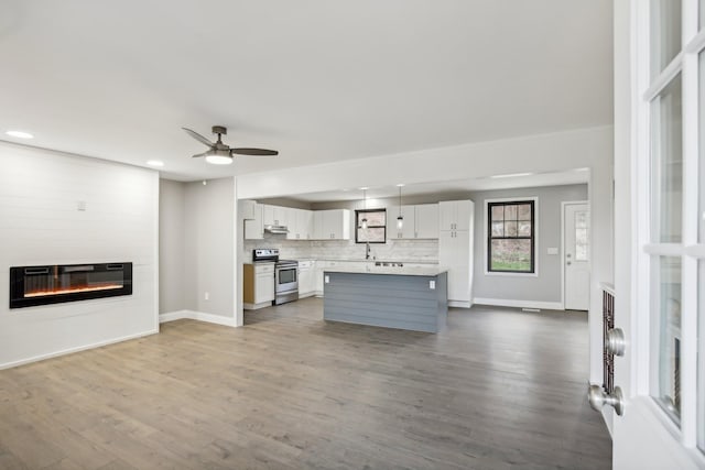 unfurnished living room with sink, hardwood / wood-style flooring, ceiling fan, a fireplace, and heating unit