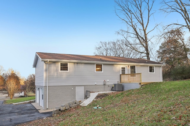 back of property featuring a lawn, central AC, and a garage