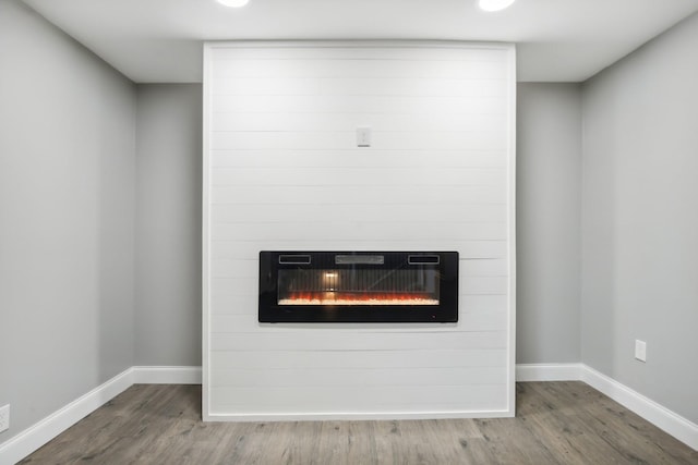 details featuring hardwood / wood-style floors, a large fireplace, and heating unit