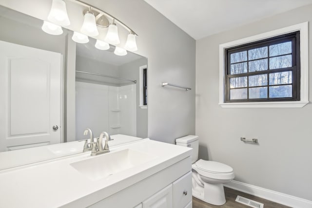 bathroom with hardwood / wood-style flooring, vanity, toilet, and walk in shower