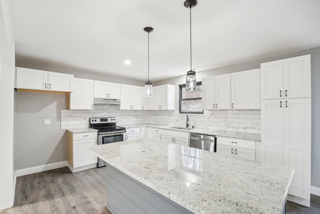 kitchen with stainless steel appliances, white cabinetry, hanging light fixtures, and sink