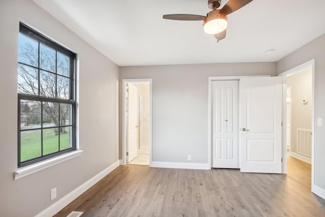 unfurnished bedroom featuring a closet, connected bathroom, ceiling fan, and light hardwood / wood-style flooring