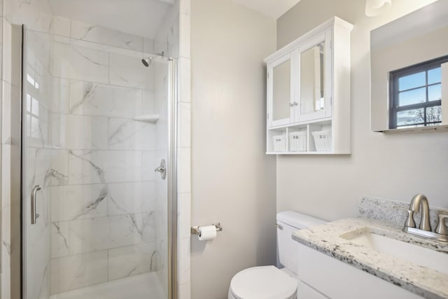 bathroom featuring vanity, a shower with shower door, and toilet