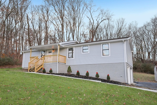 view of front of home featuring covered porch, a garage, and a front lawn