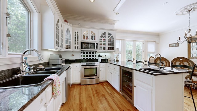 kitchen featuring white cabinetry, wine cooler, plenty of natural light, decorative light fixtures, and appliances with stainless steel finishes