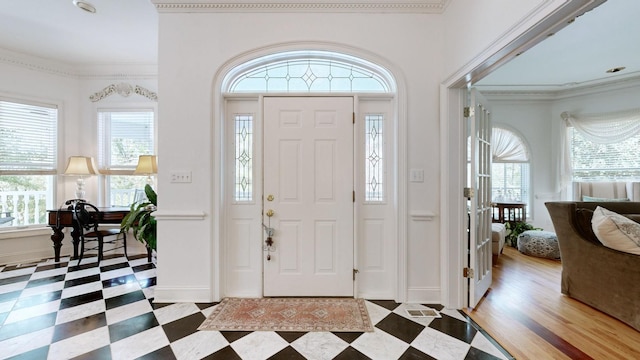 entryway with light wood-type flooring, plenty of natural light, and ornamental molding