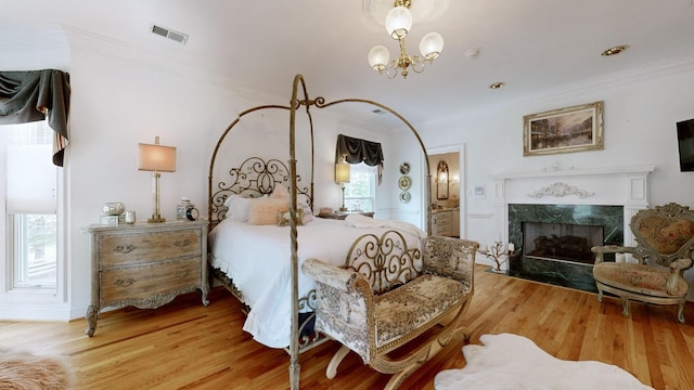 bedroom featuring a fireplace, light wood-type flooring, and ornamental molding