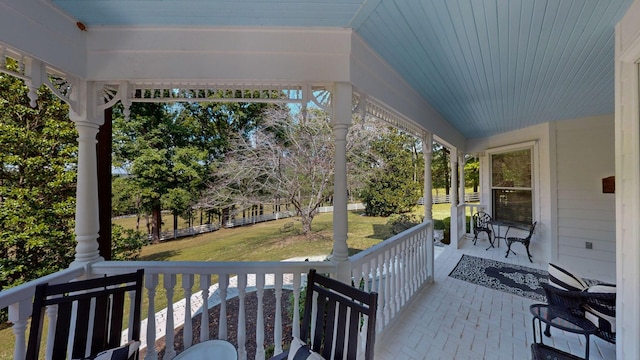 wooden deck featuring covered porch and a yard