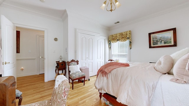 bedroom with light wood-type flooring, a closet, ornamental molding, and a notable chandelier