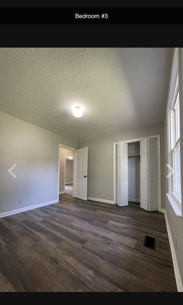 unfurnished bedroom featuring dark hardwood / wood-style flooring, a textured ceiling, and a closet