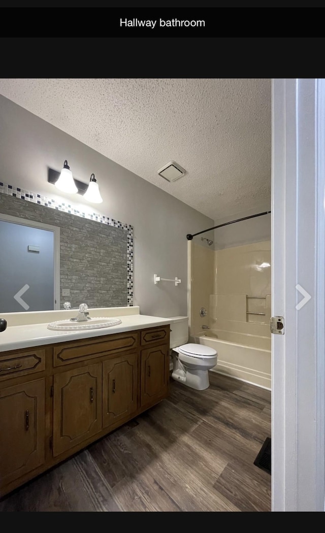 full bathroom featuring vanity, wood-type flooring, a textured ceiling, and bathing tub / shower combination