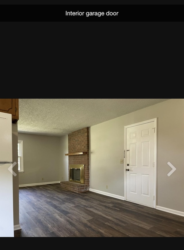 unfurnished living room featuring dark hardwood / wood-style flooring, a textured ceiling, and a brick fireplace