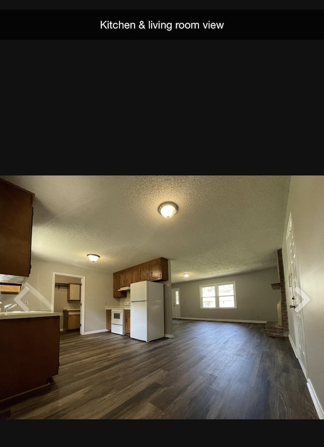 kitchen with a textured ceiling, a fireplace, white refrigerator, and dark wood-type flooring