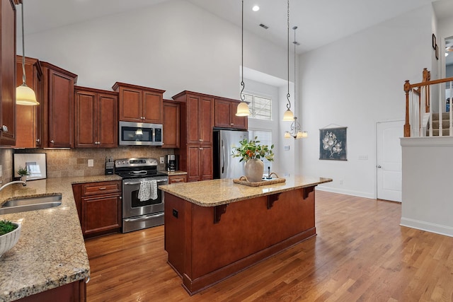 kitchen featuring a center island, sink, stainless steel appliances, high vaulted ceiling, and wood-type flooring