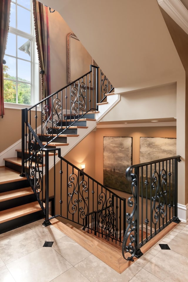 stairway featuring hardwood / wood-style floors, ornamental molding, and a high ceiling