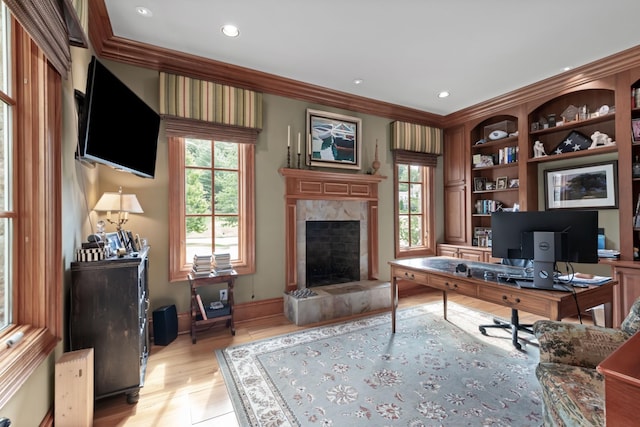 office space featuring crown molding, a fireplace, and light hardwood / wood-style flooring