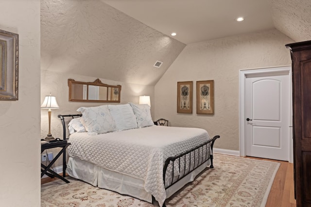 bedroom featuring hardwood / wood-style flooring, a textured ceiling, and vaulted ceiling