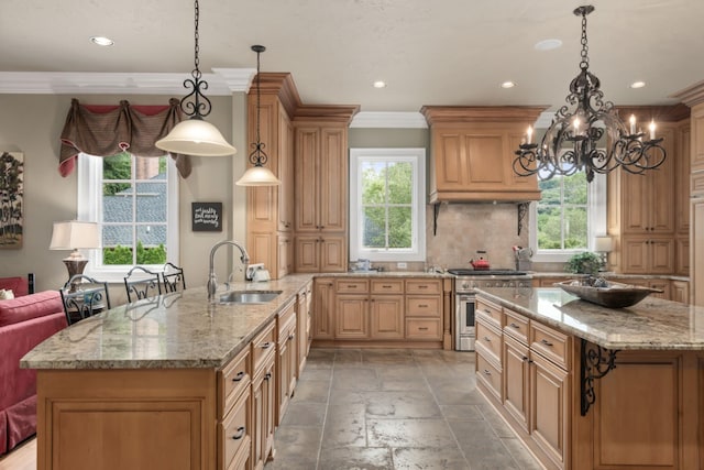 kitchen featuring high end stove, backsplash, a center island with sink, and sink