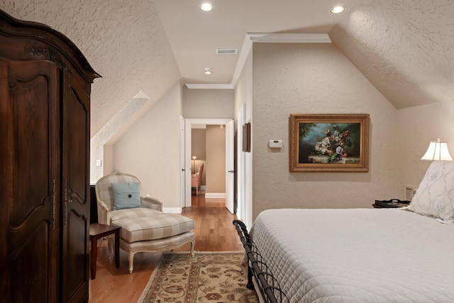 bedroom with wood-type flooring, vaulted ceiling, and ornamental molding