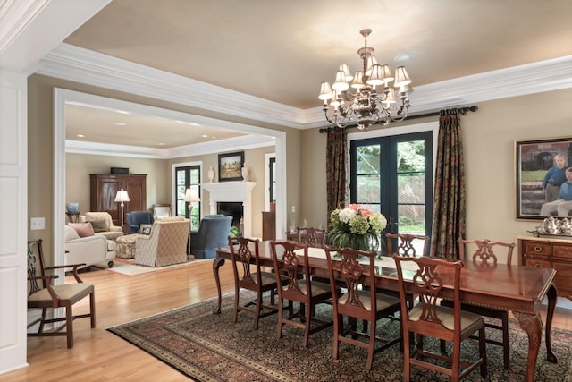 dining area with a tray ceiling, crown molding, light hardwood / wood-style floors, and a notable chandelier