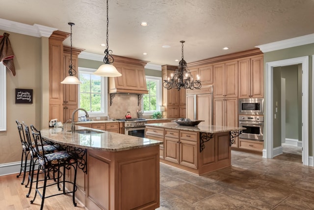 kitchen with built in appliances, a kitchen island, sink, and hanging light fixtures