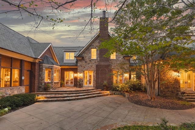 back house at dusk with french doors and a patio