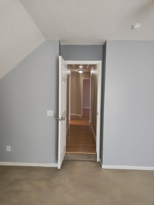 hallway featuring lofted ceiling and carpet flooring