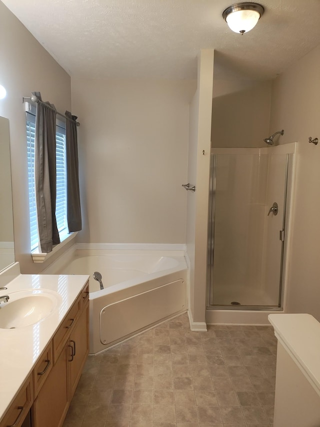 bathroom with a textured ceiling, vanity, and shower with separate bathtub