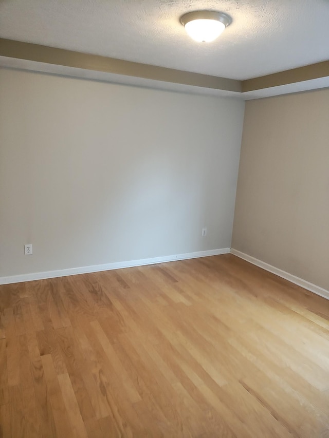 spare room with a textured ceiling and light wood-type flooring