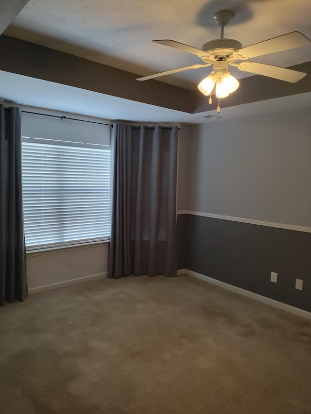 carpeted spare room featuring ceiling fan and a raised ceiling