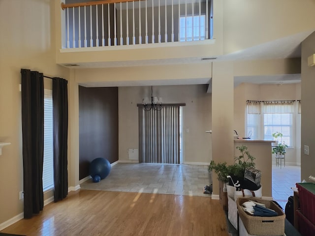 entryway with a towering ceiling, light wood-type flooring, and a chandelier