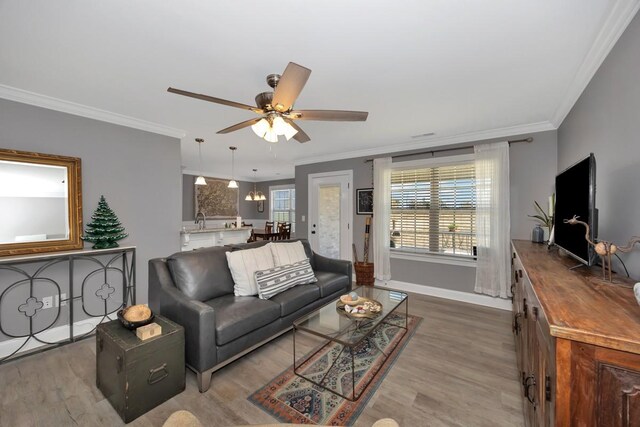 living room featuring crown molding, light hardwood / wood-style flooring, and ceiling fan