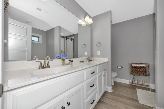 bathroom with vanity, hardwood / wood-style flooring, toilet, and walk in shower