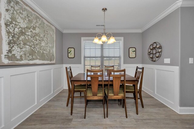 dining area featuring an inviting chandelier, light hardwood / wood-style flooring, and ornamental molding