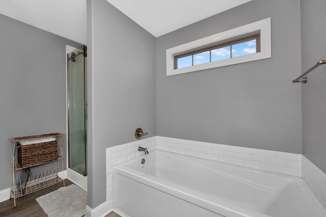 bathroom featuring a tub to relax in, vaulted ceiling, and hardwood / wood-style flooring