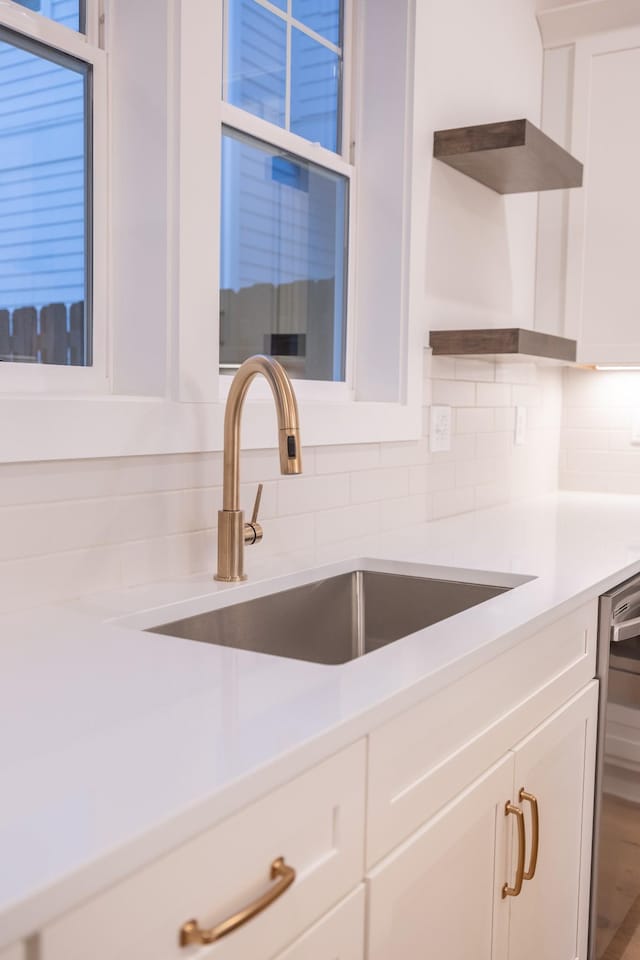 kitchen featuring backsplash, sink, wood-type flooring, dishwasher, and white cabinets