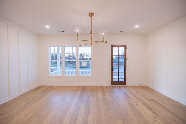 unfurnished dining area with light wood-type flooring and a chandelier