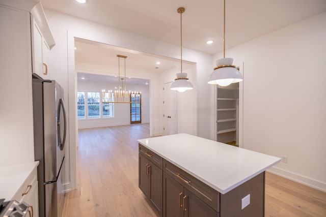 kitchen featuring pendant lighting, stainless steel fridge, dark brown cabinetry, and light hardwood / wood-style flooring