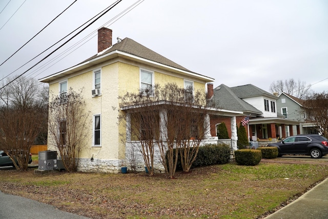 view of front of house featuring covered porch, central AC unit, cooling unit, and a front yard