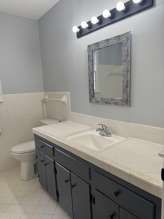 bathroom with tile patterned flooring, tile walls, vanity, and toilet