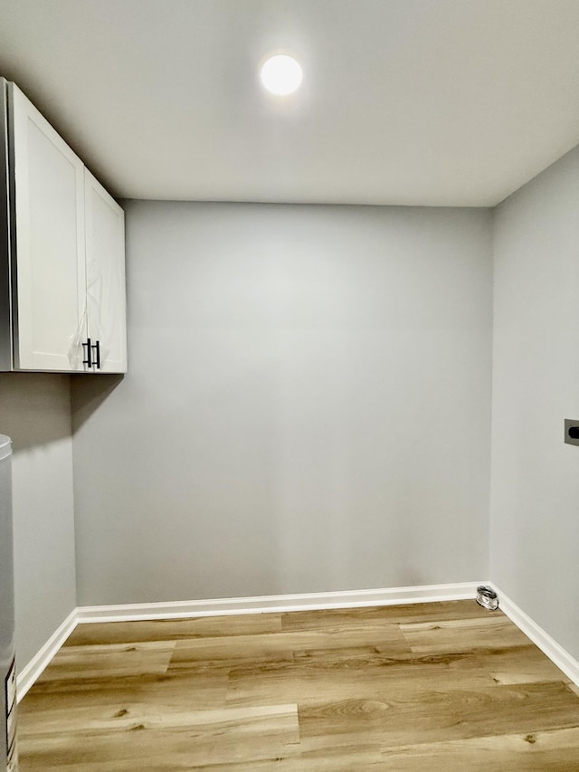 laundry area with electric dryer hookup, cabinets, and hardwood / wood-style flooring