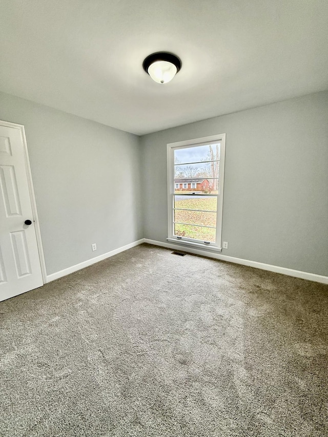 carpeted spare room featuring baseboards