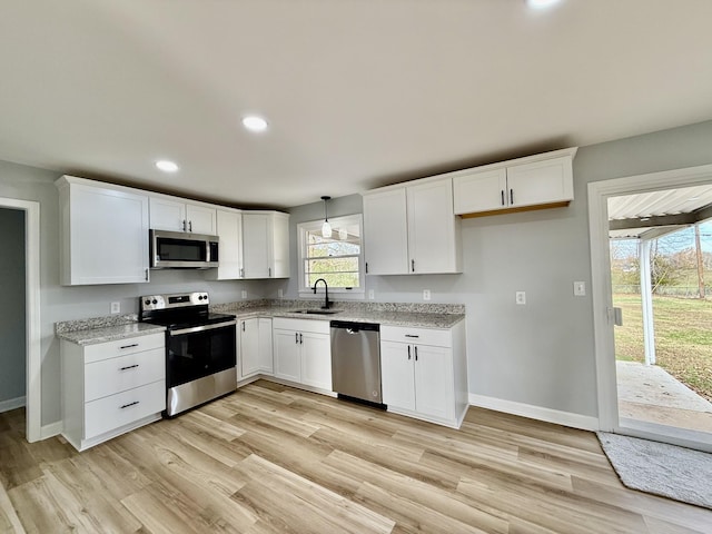 kitchen with pendant lighting, white cabinets, sink, light hardwood / wood-style floors, and stainless steel appliances