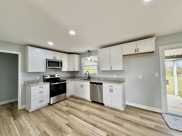 kitchen featuring white cabinetry, pendant lighting, light hardwood / wood-style floors, and appliances with stainless steel finishes