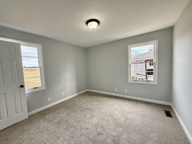 unfurnished room featuring baseboards, carpet flooring, visible vents, and a healthy amount of sunlight